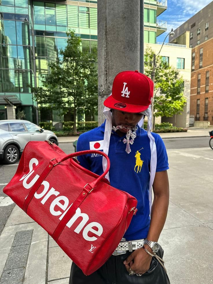 Higgsfield Soul ID test image: a man in a red LA cap and blue polo holding a red Supreme duffel bag on a city street